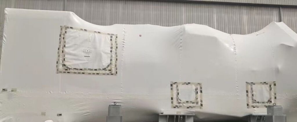 Heavy industrial equipment securely wrapped in GreenVCI Shrink Film, providing dual physical and chemical corrosion protection for oversized metal structures, ideal for shipping and outdoor storage.